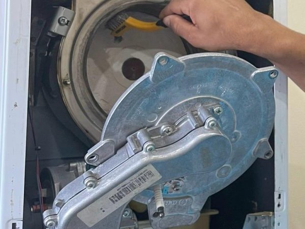Engineer servicing the internals of a gas boiler with the casing removed