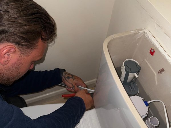 Plumber fitting a bath and connecting the waste and supply pipework