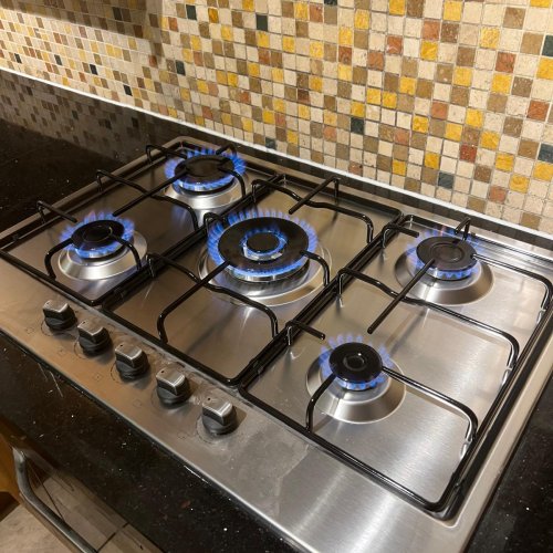 Five-burner stainless steel gas hob lit and tested after installation